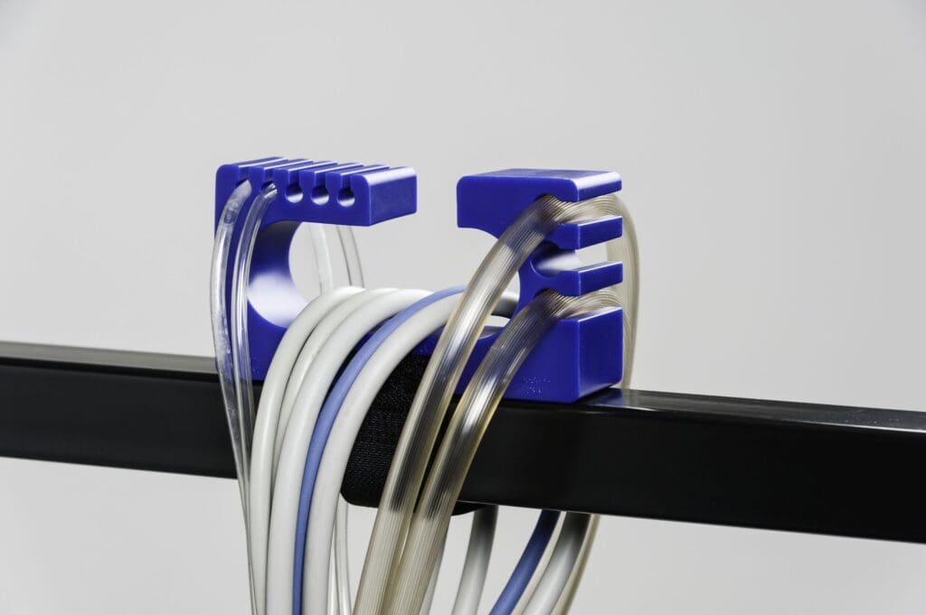 A blue plastic holder with many wires hanging from it.