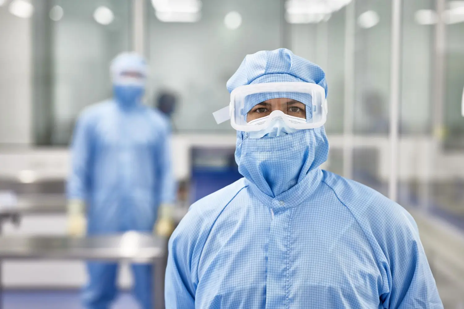 Two people in blue lab coats and masks